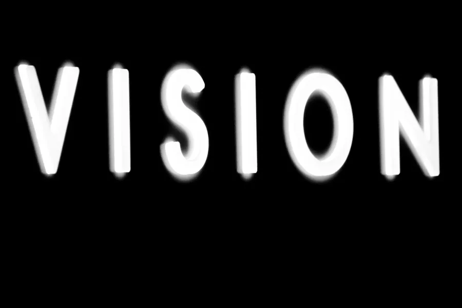 Weiss leuchtende Buchstaben auf schwarzem Grund: VISION