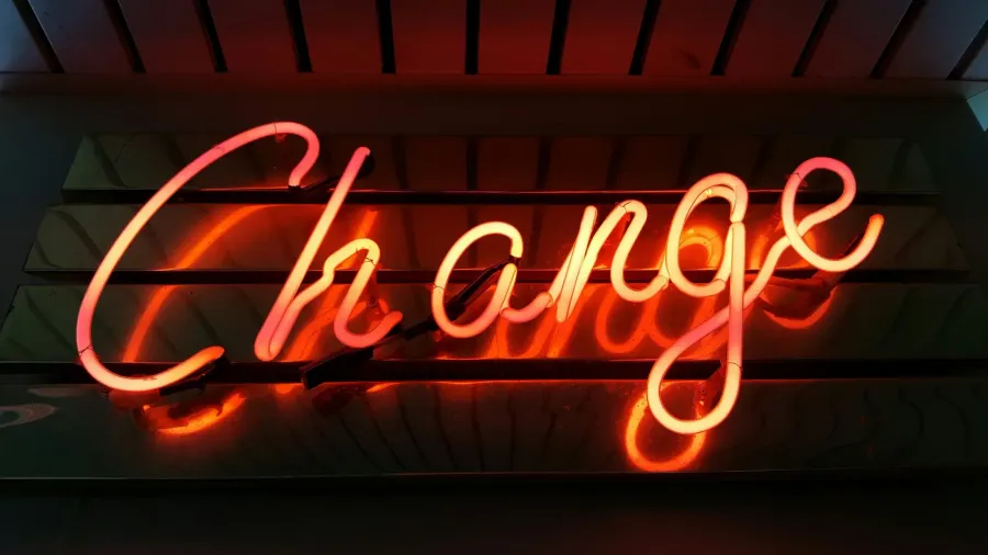 Ein Neonschriftzug „Change“ leuchtet rot vor einer dunklen Wand